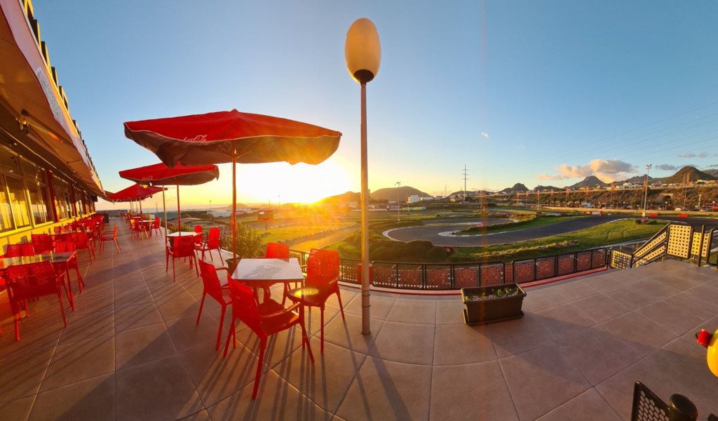 Restaurant terrace with red tables and sunset view on a circuit in Tenerife.