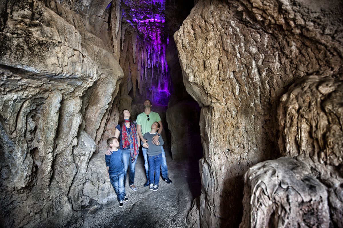Family exploring a cave in Tenerife, purple lighting highlighting the interior.
