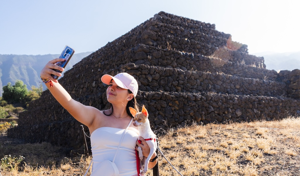 Person taking a selfie with a dog in front of the Pyramids of Güímar in Tenerife.