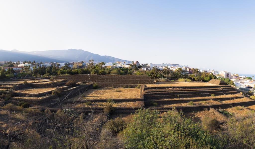Pyramids of Güímar in Tenerife with mountains and city in the background.