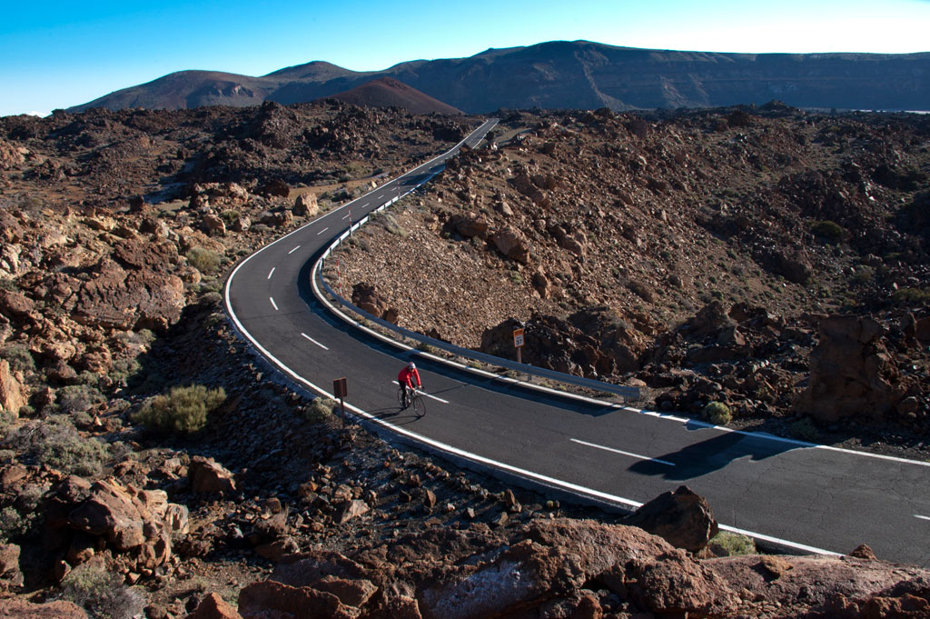 Cyclist on the road between rocks in the Teide National Park in Tenerife.