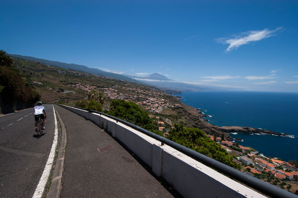 Cyclist riding a road with views of Mount Teide and the coast in Tenerife.