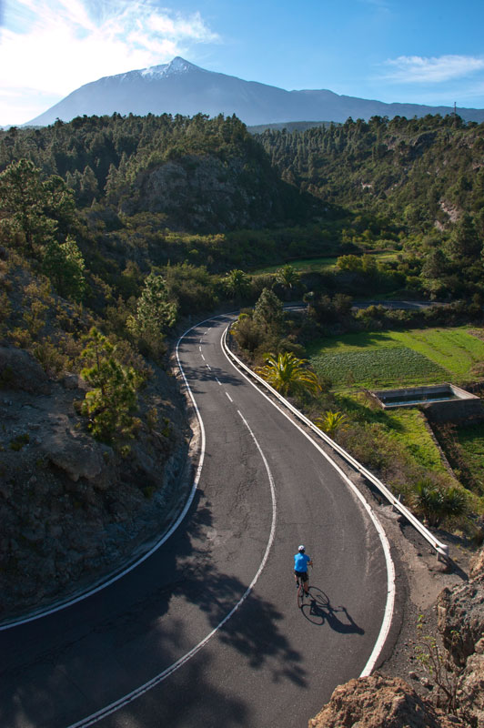 Road cyclist surrounded by mountains and greenery in Tenerife.