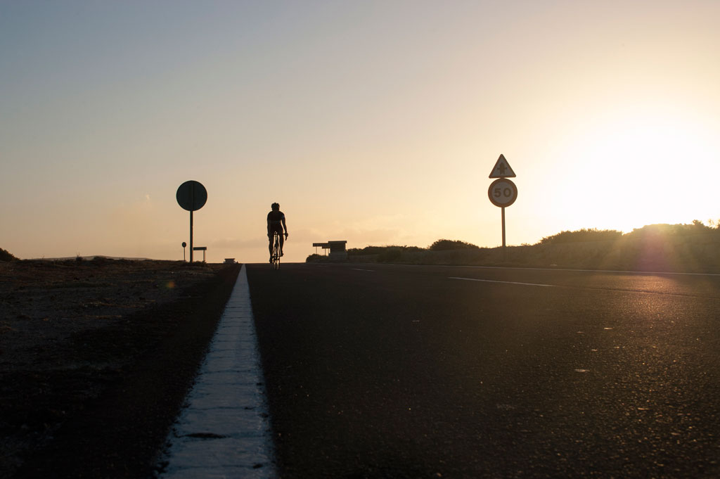 Cyclist at sunset on the road in Tenerife with a limit of 50.