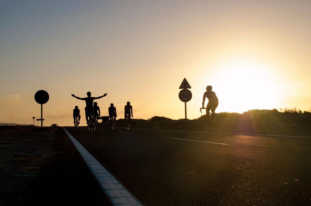 Cyclists on the road at sunset in Tenerife, next to a speed sign 50.