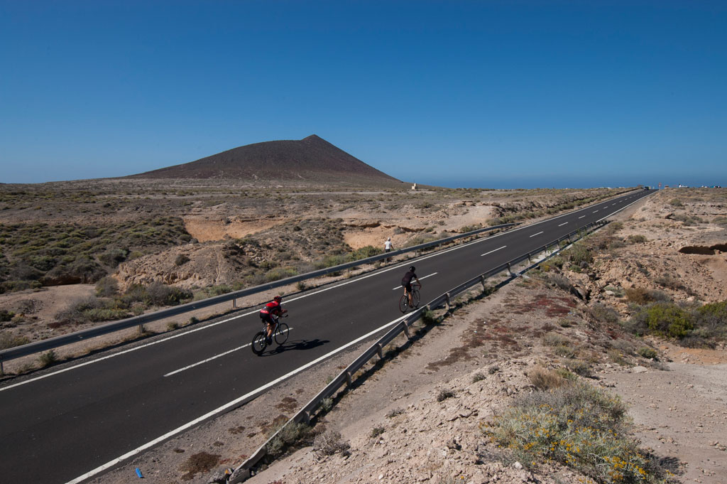 Cyclists on the road to the mountains in Tenerife under clear skies.