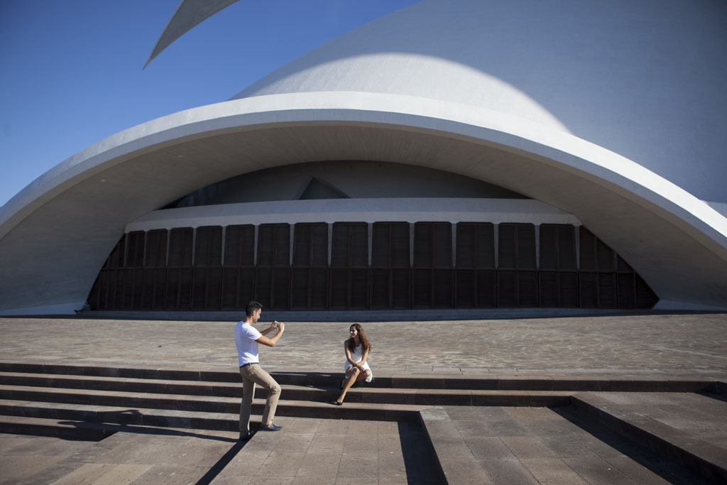 Person taking a photo of another in front of the Auditorio de Tenerife.