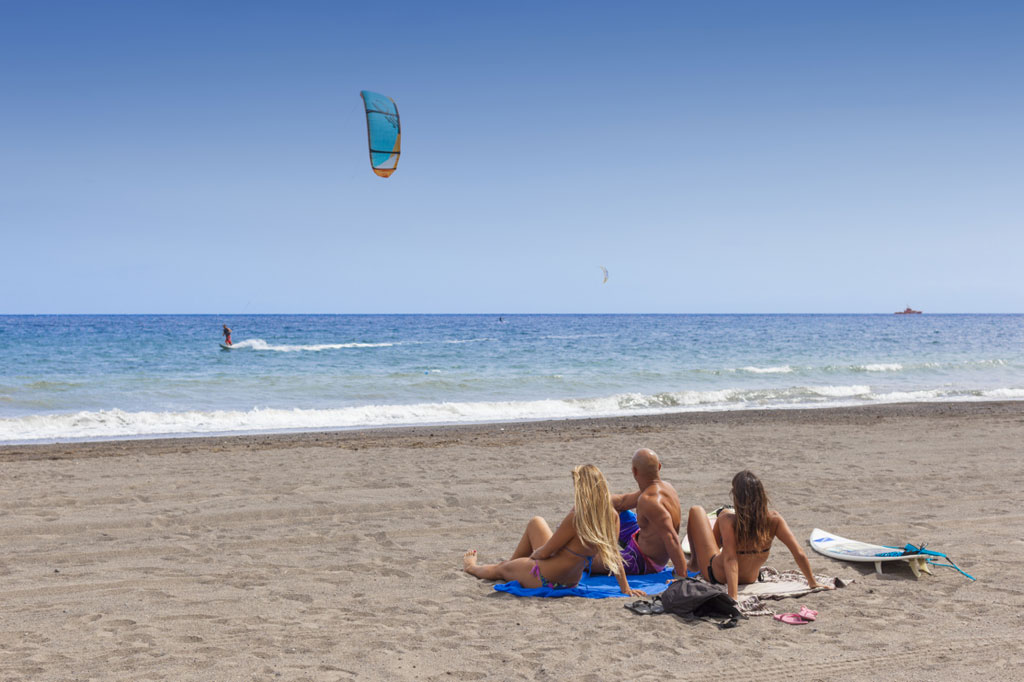 People watching a kitesurfer on the beach of El Médano, Tenerife.