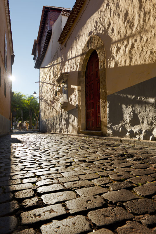 Cobbled street with arched door and sunlight in La Laguna, Tenerife.