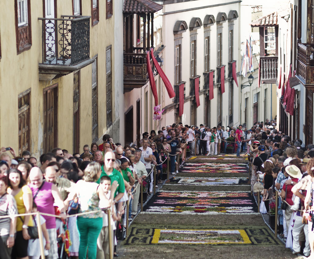 People gather in La Orotava, Tenerife, during a festive celebration with floral carpets in the street.