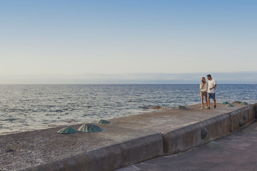 Couple walking along the pier by the sea in Tenerife.