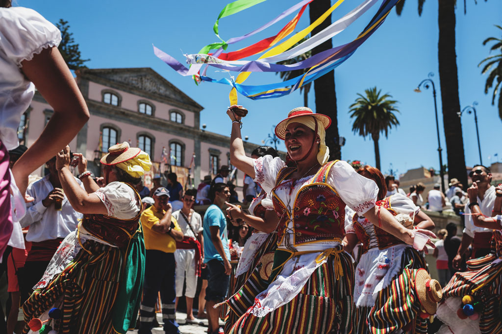 People dancing in traditional costumes with ribbons at a festival in Tenerife.