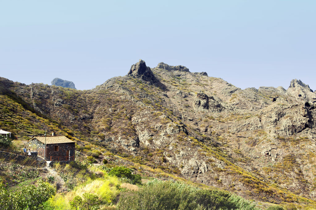 Stone house in the mountainous landscape of Masca, Tenerife, with vegetation all around.