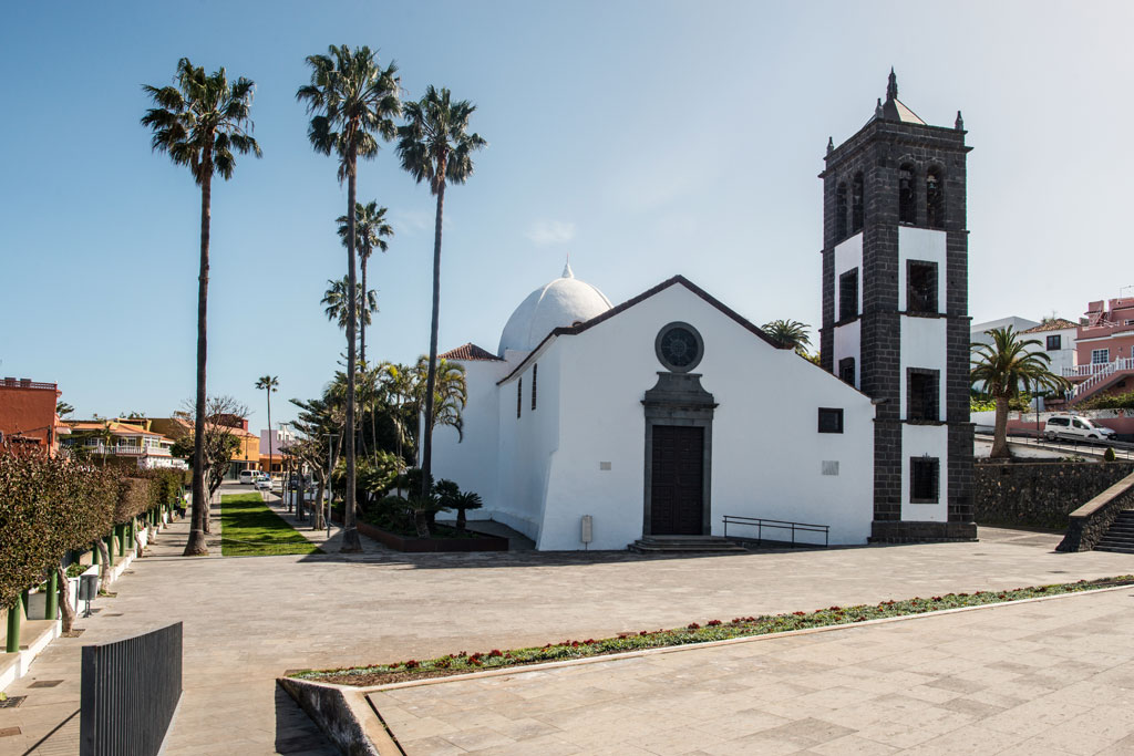 Church of San Juan Bautista with its bell tower and palm trees around in La Orotava, Tenerife.
