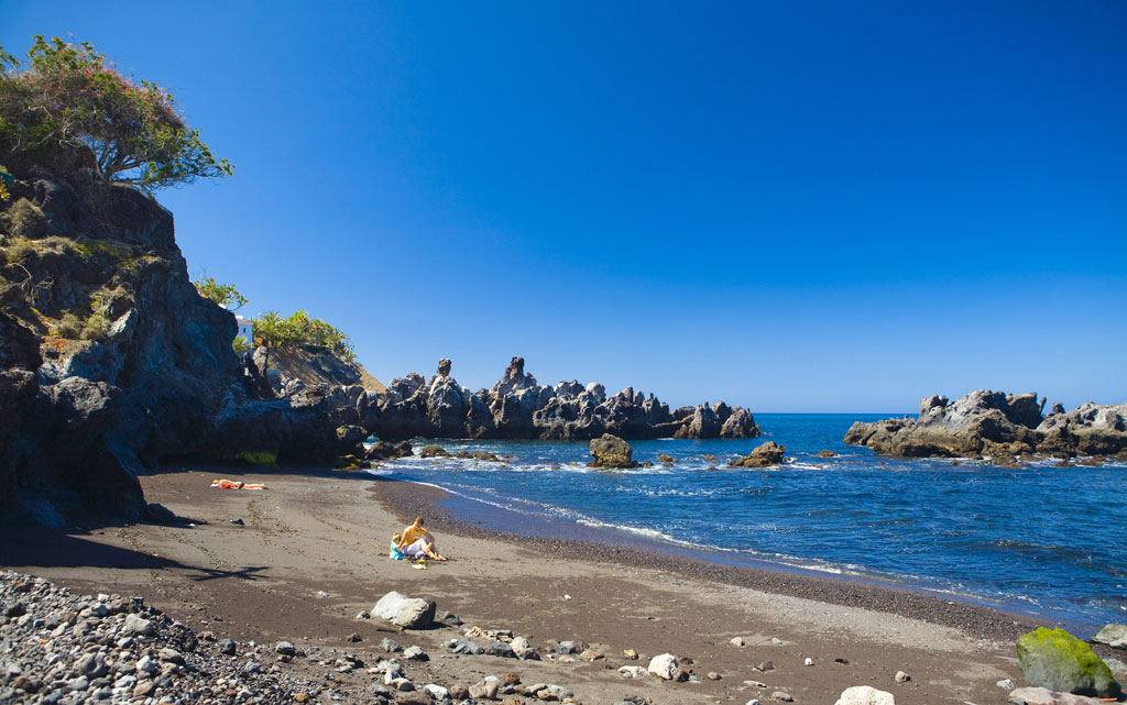 Beach with rocks and sea view in Tenerife, under a clear sky.