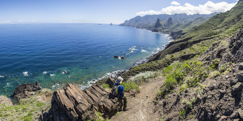 Coastal path with sea and mountain views in Tenerife. Person walking.