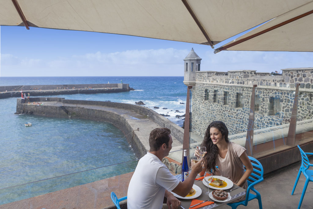 Couple having lunch on a terrace overlooking the sea in Puerto de la Cruz, Tenerife.