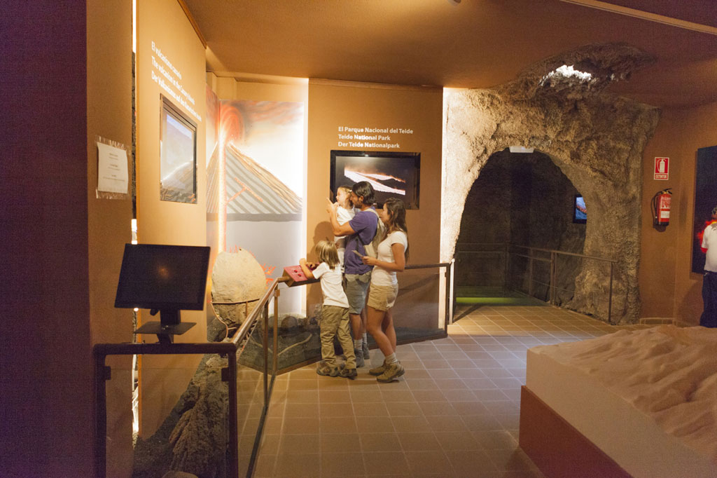 Visitors observe the exhibition of the Teide National Park inside a simulated cave.