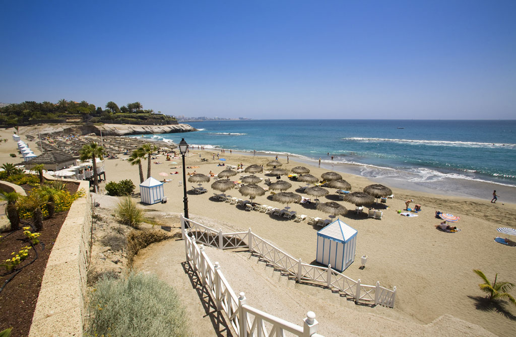 Playa del Duque in Tenerife with umbrellas and bathers enjoying the sun.