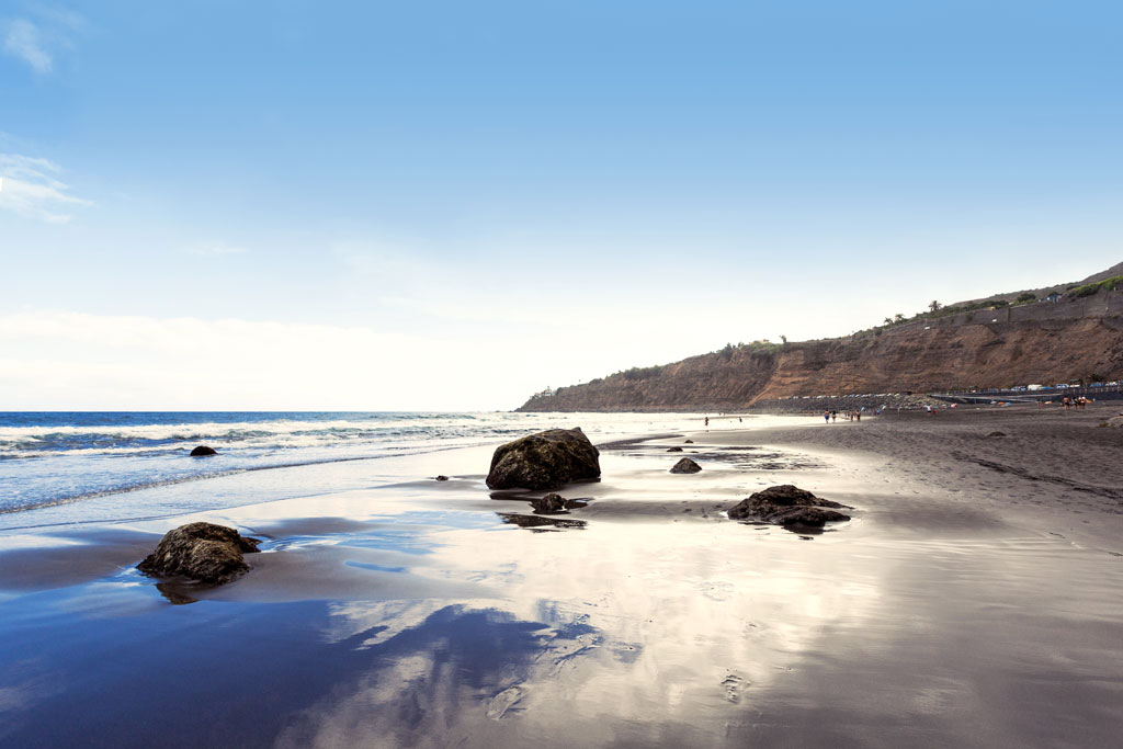 Black sand beach with rocks and cliffs in Tenerife.