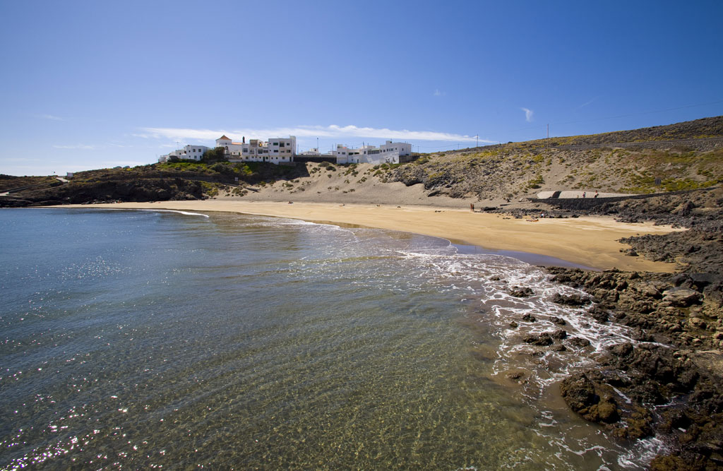 Beach with golden sand and buildings in the background on the coast of Tenerife.