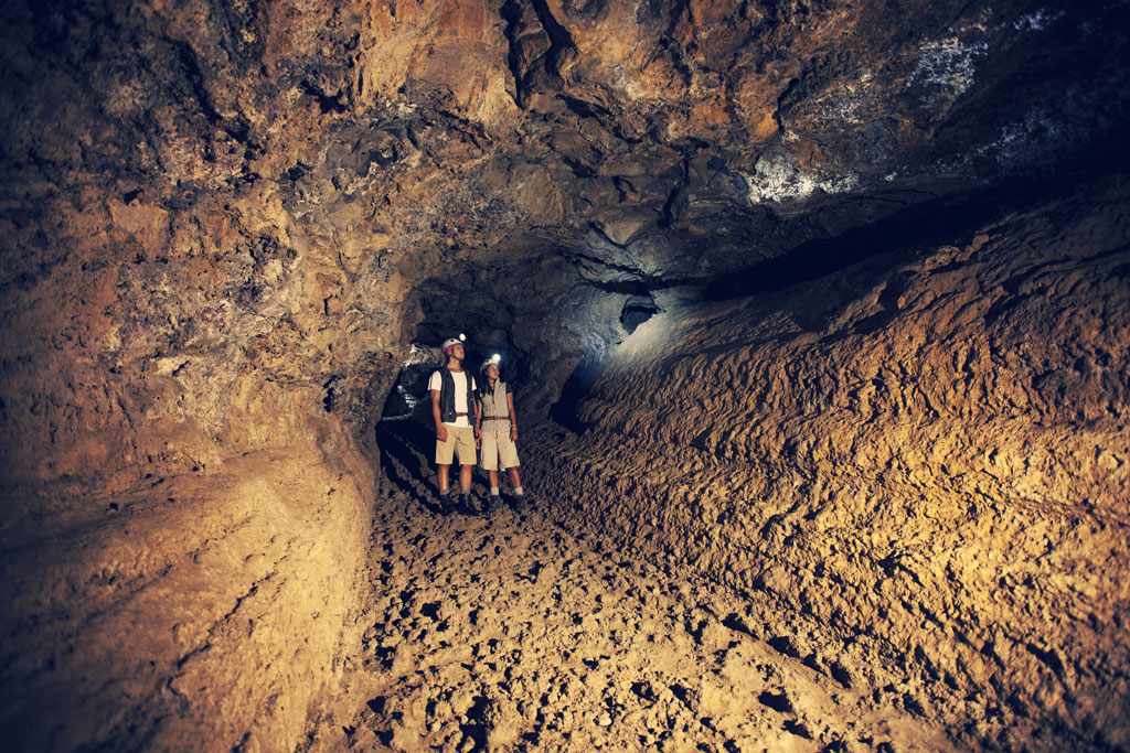 People exploring the inside of the volcanic tube in Cueva del Viento, Tenerife.