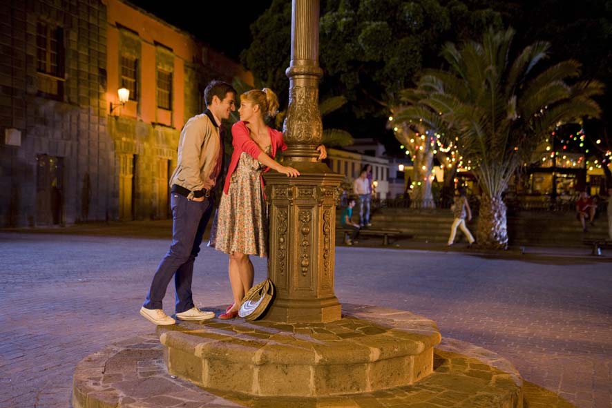 Couple chatting next to a lamppost in an illuminated square in La Laguna, Tenerife.
