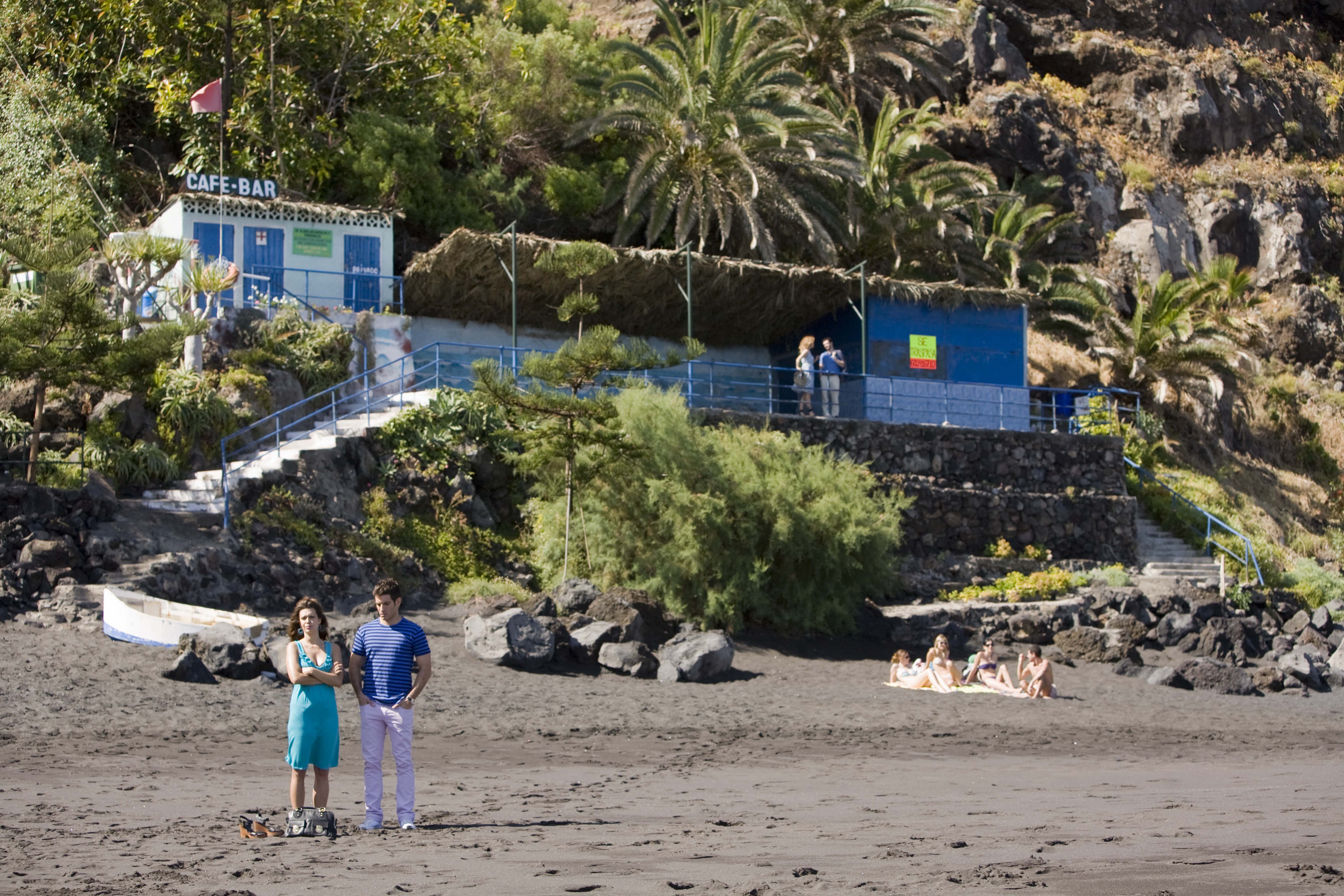 Couple on the beach in front of a café-bar in Puerto de la Cruz, Tenerife.