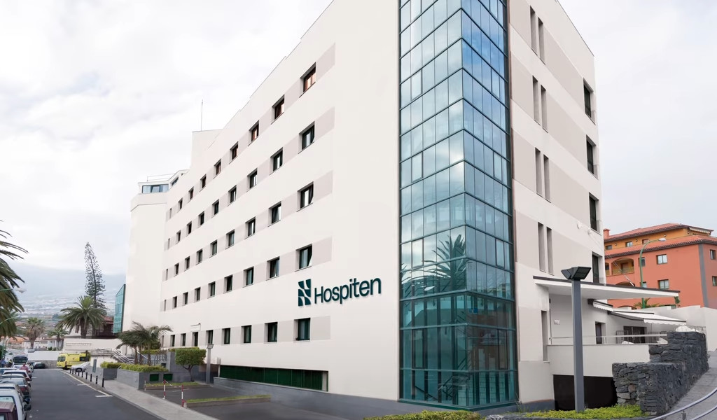 Hospiten hospital building in Tenerife with a white façade and large windows.