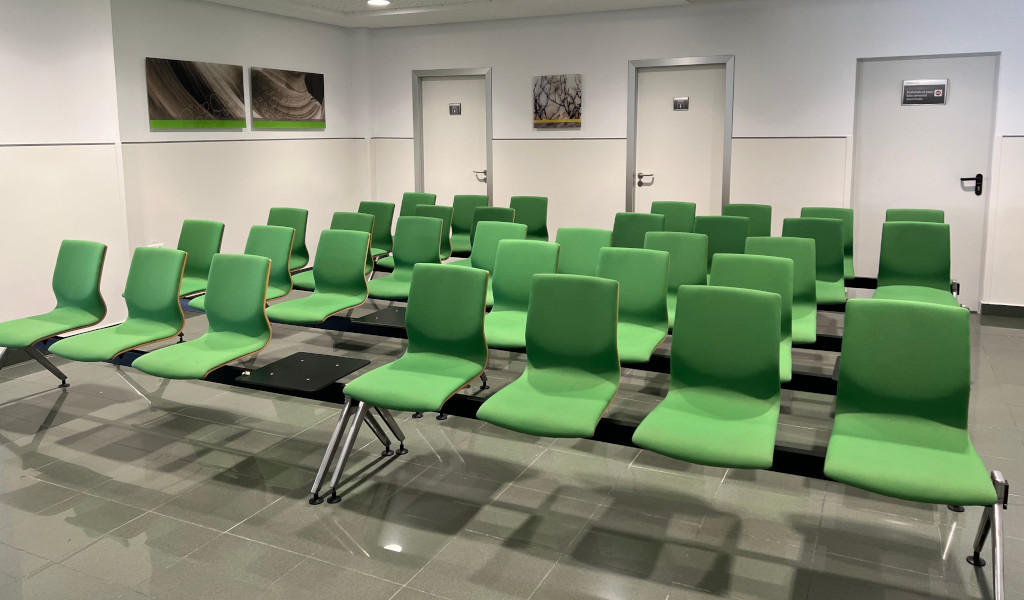 Waiting room with green chairs in Tenerife. Doors and pictures on the wall.
