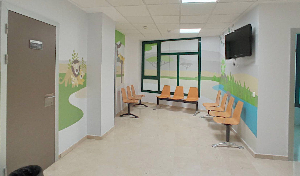 Waiting room with orange chairs and colorful murals in Tenerife.