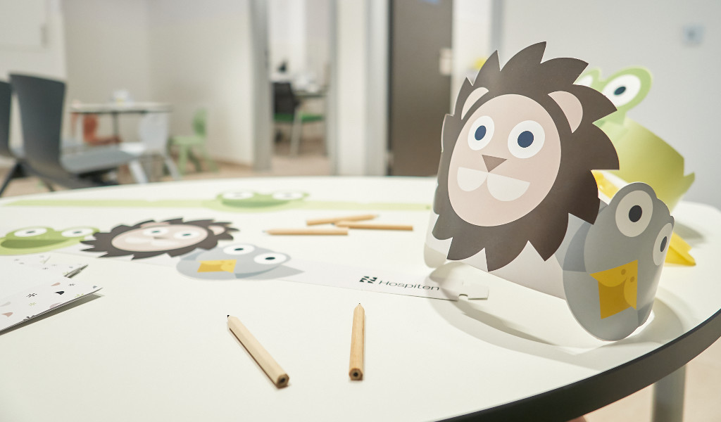 Table with craft materials for children in a hospital in Tenerife, including paper wreaths with animal designs.
