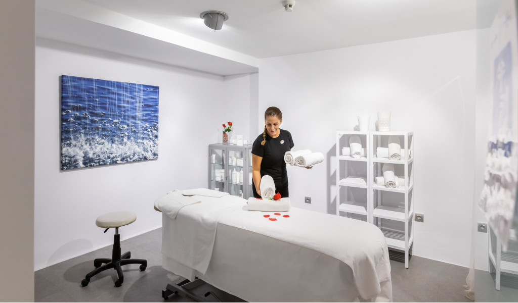 Massage room with therapist arranging white towels in Tenerife.