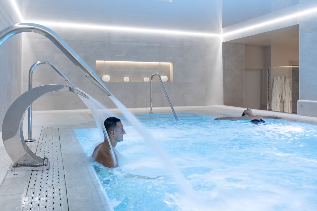 Man enjoying indoor pool with water jet in Tenerife spa.