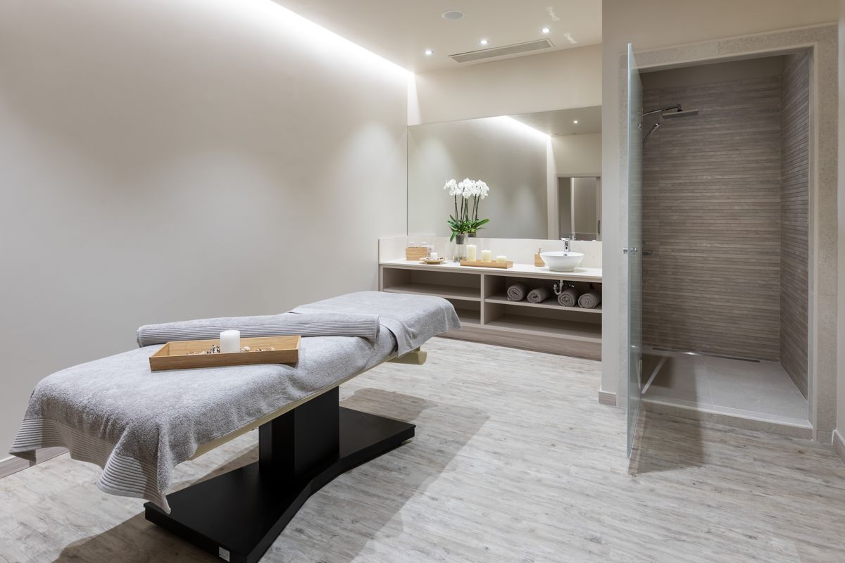 Spa room with stretcher, towels, and orchids; relaxing atmosphere in Tenerife.