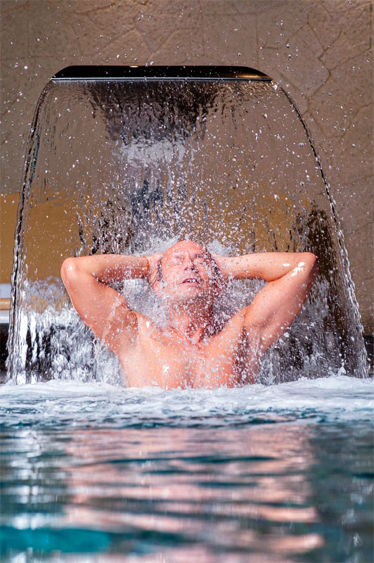 Person under waterfall in Tenerife spa.