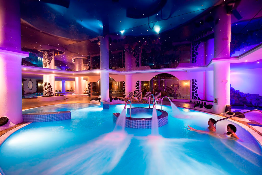Illuminated indoor pool in a spa in Tenerife with two people relaxing.