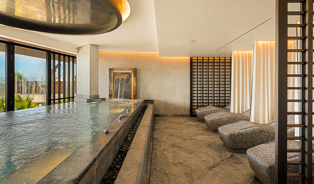 Indoor spa with pool and sun loungers near window in Adeje, Tenerife.