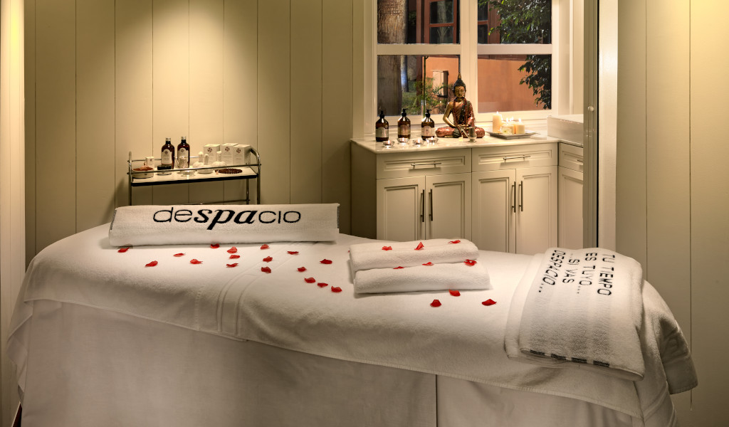 Massage room with towels and red petals in Tenerife. Visible text: slowly, your time is....