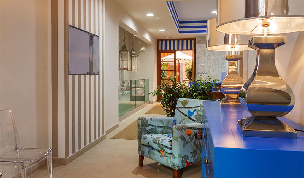 Interior corridor with patterned armchair and lamps, entrance to outdoor patio in Tenerife.