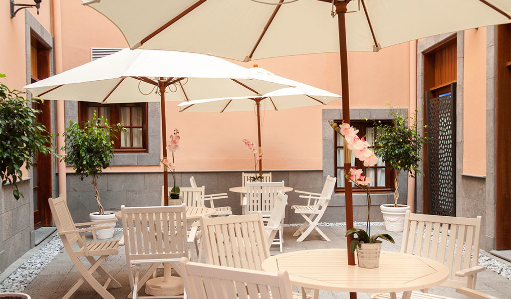 Terrace with white tables and chairs under umbrellas in a courtyard in Tenerife.