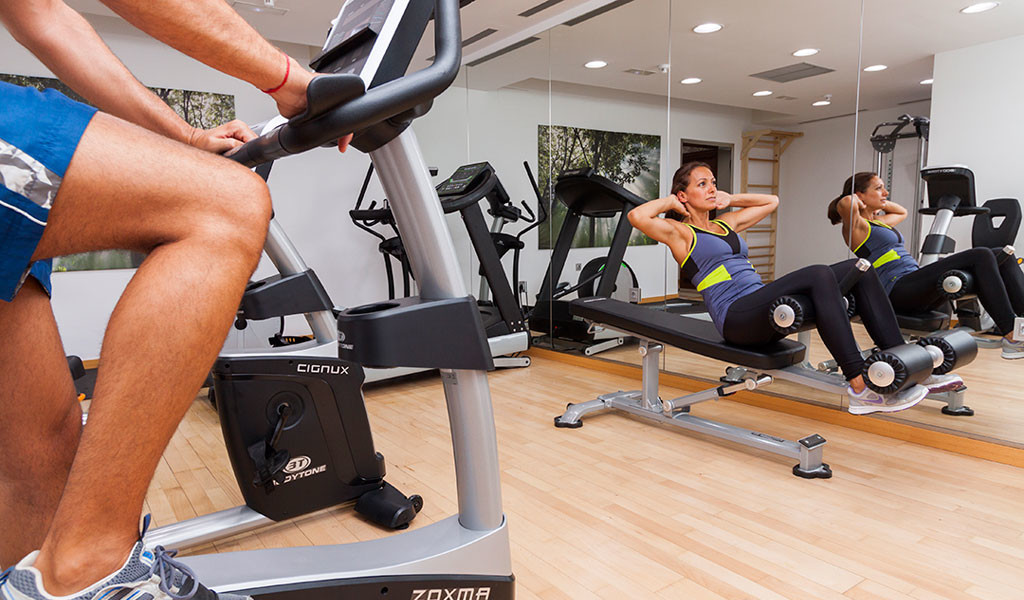 Person on exercise bike and woman doing sit-ups in gym in Tenerife.