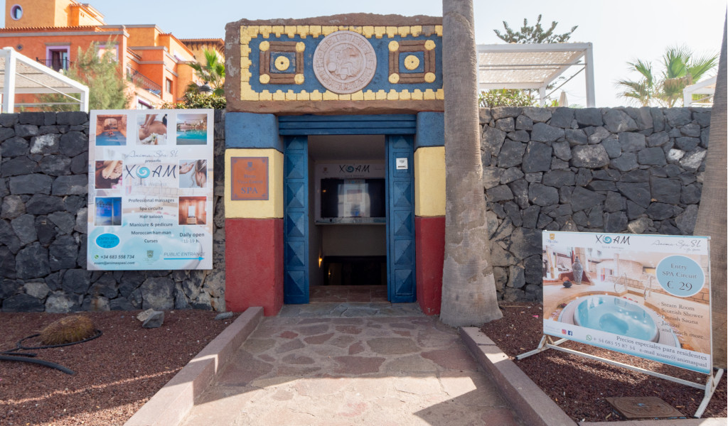 Entrance to the XQANM spa with advertising posters in Tenerife.