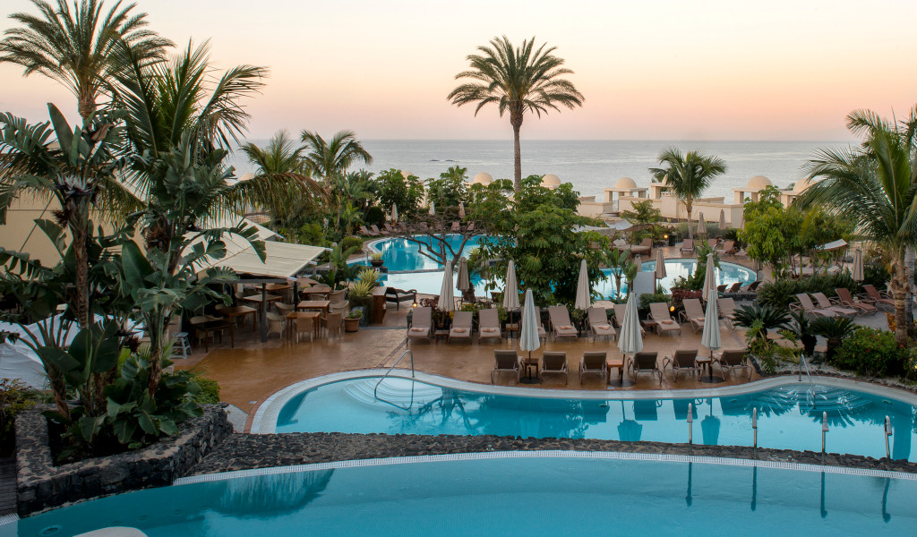 Hotel swimming pool in Tenerife with sea views at sunset.