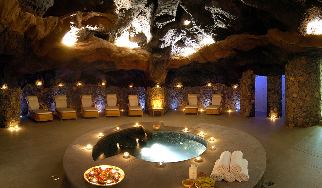 Cave with jacuzzi surrounded by chairs and candles in a spa in Tenerife.