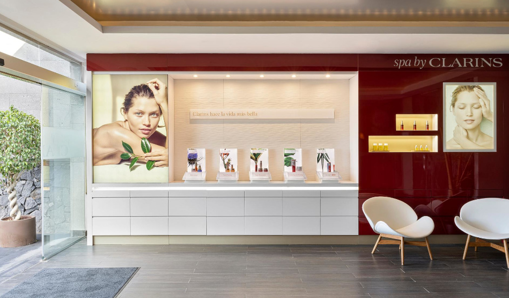 Reception of the Clarins spa in Tenerife with posters of models and products. Text: Clarins makes life more beautiful.