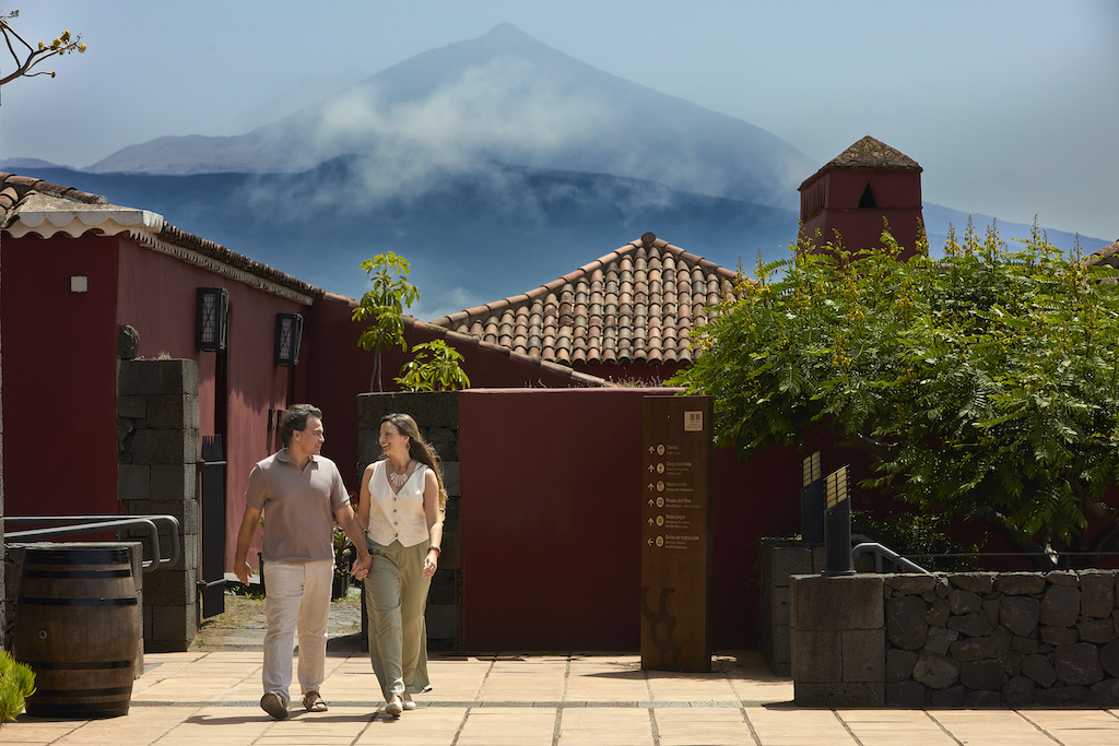 People walking near traditional houses with Mount Teide in the background in Tenerife.