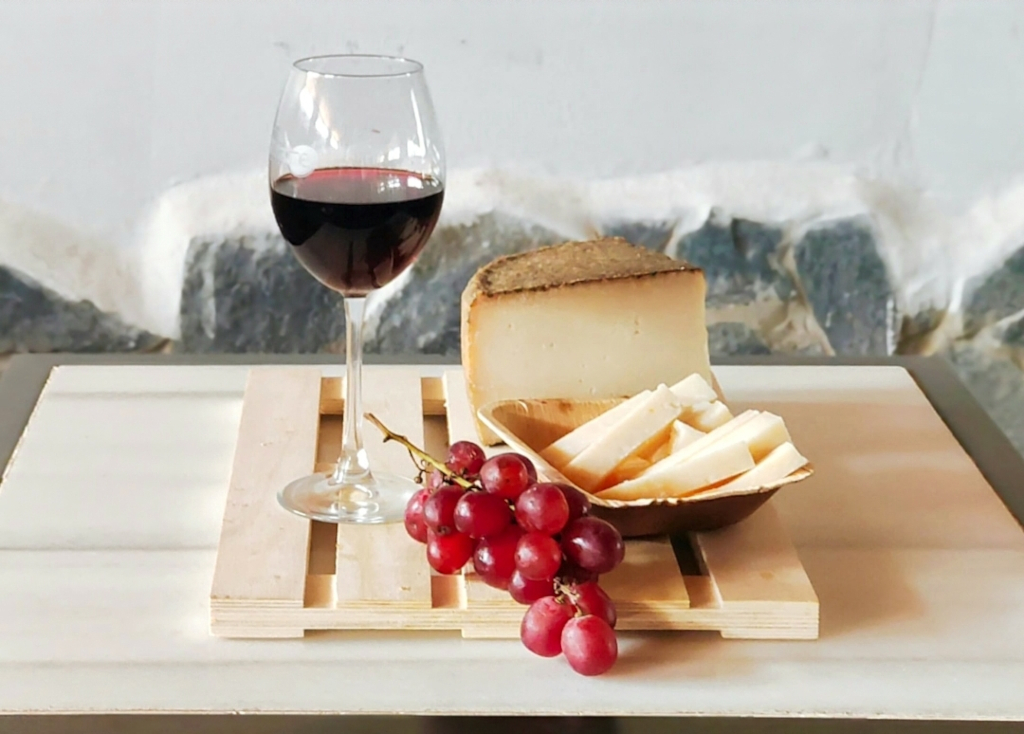 Glass of red wine, cheese and red grapes on a board in Tenerife.