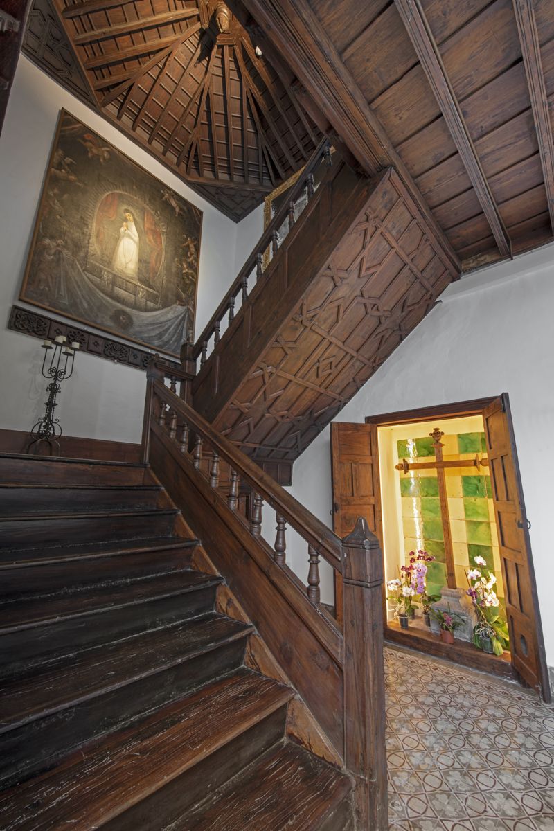 Wooden staircase with religious painting and stained glass window in a house in Tenerife.