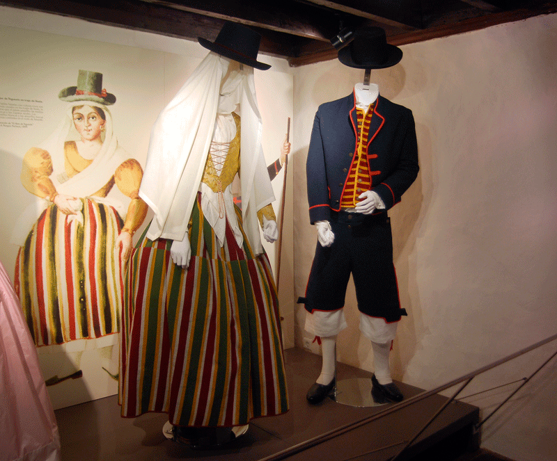 Typical costumes of Tenerife on display, with historical illustration background.
